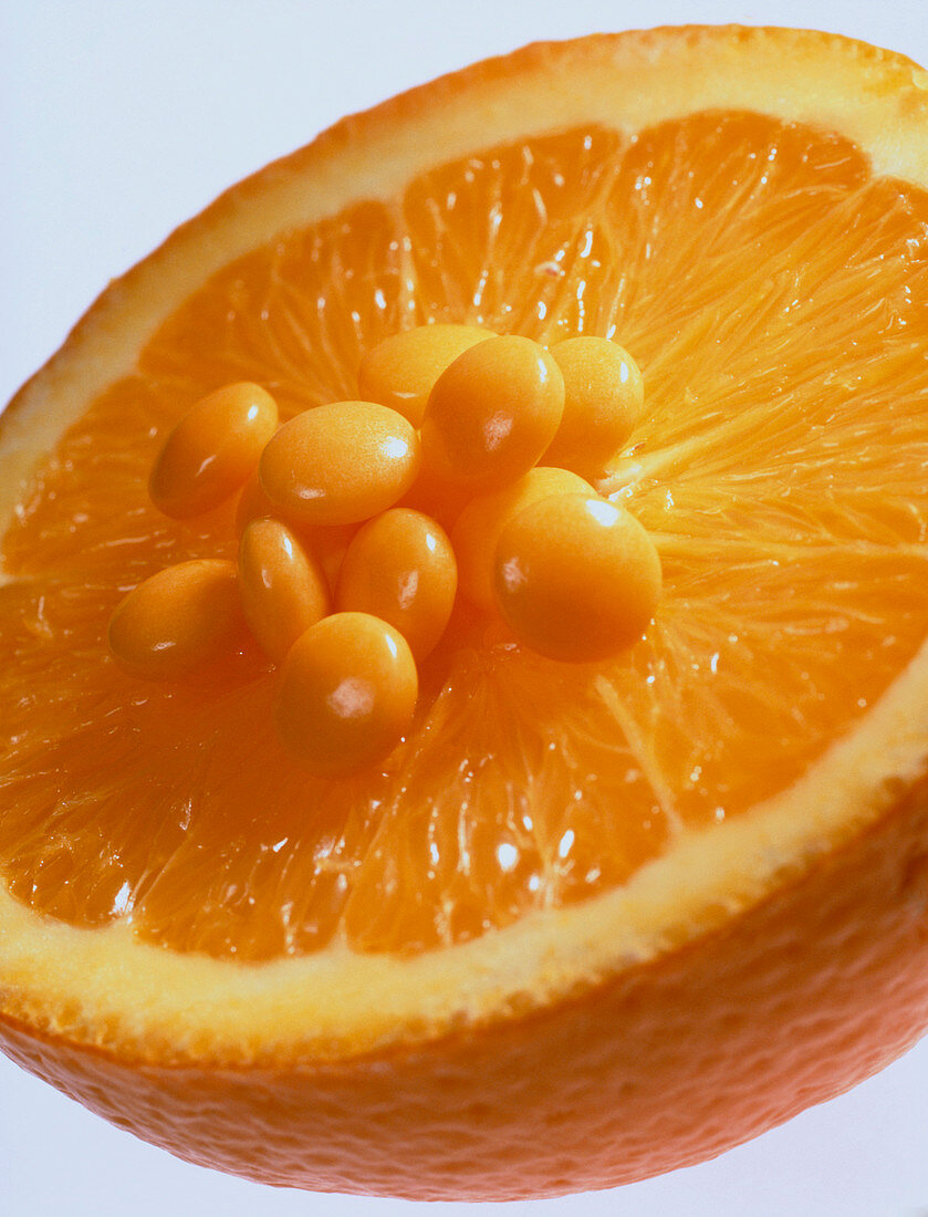 View of vitamin C pills on an orange half
