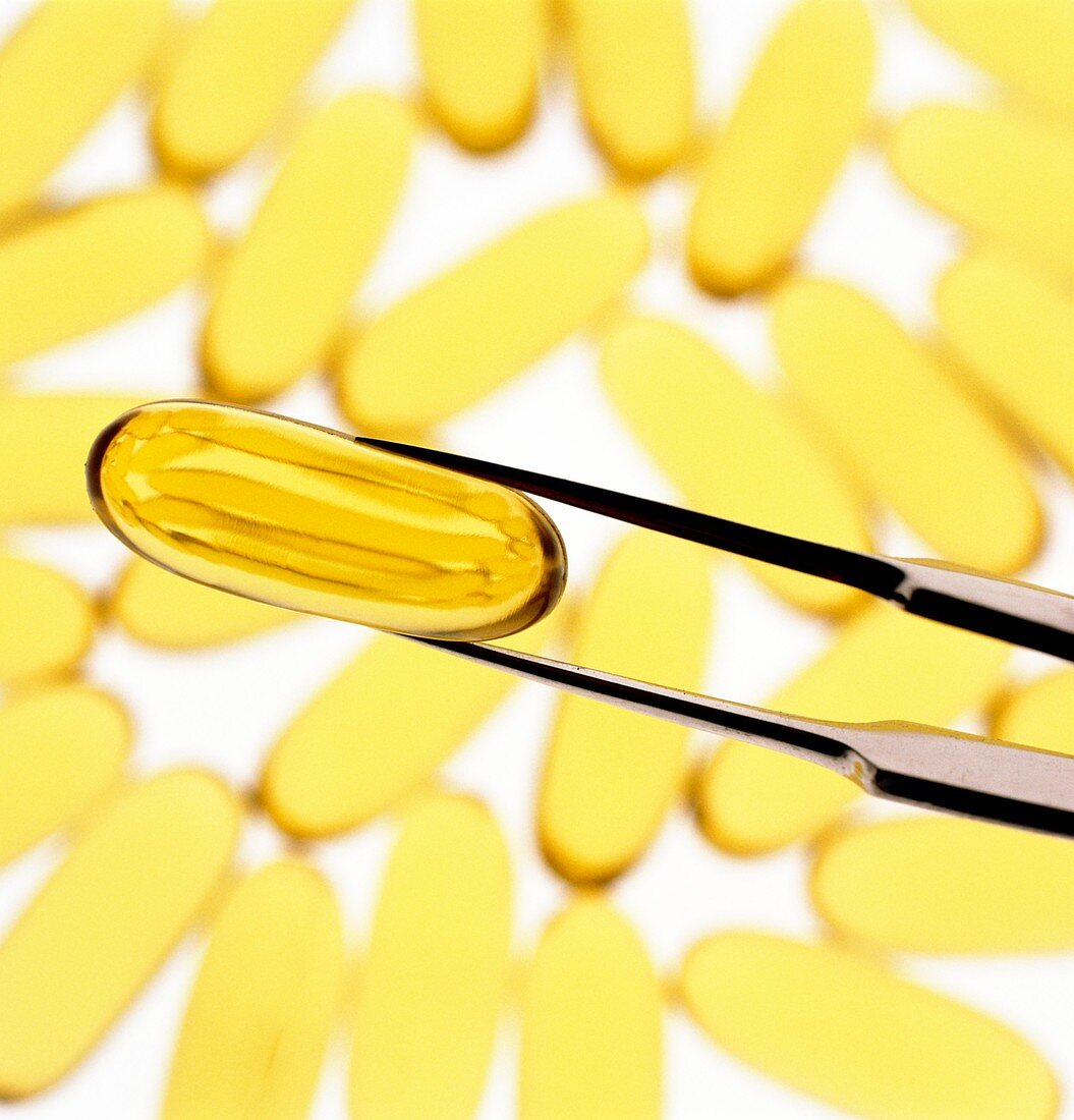 Tweezers holding a capsule of oil or vitamin E