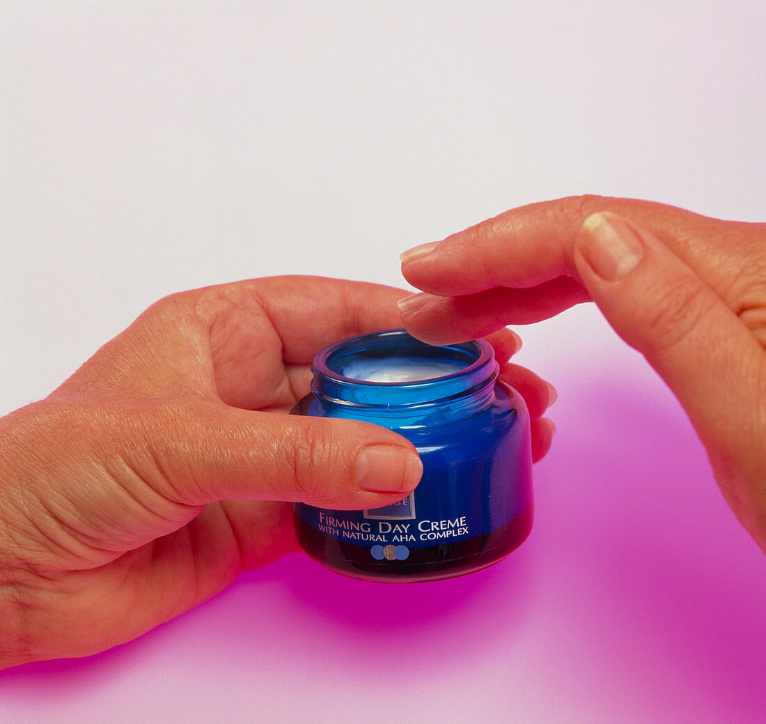 Hands take anti-aging moisturiser cream from a jar