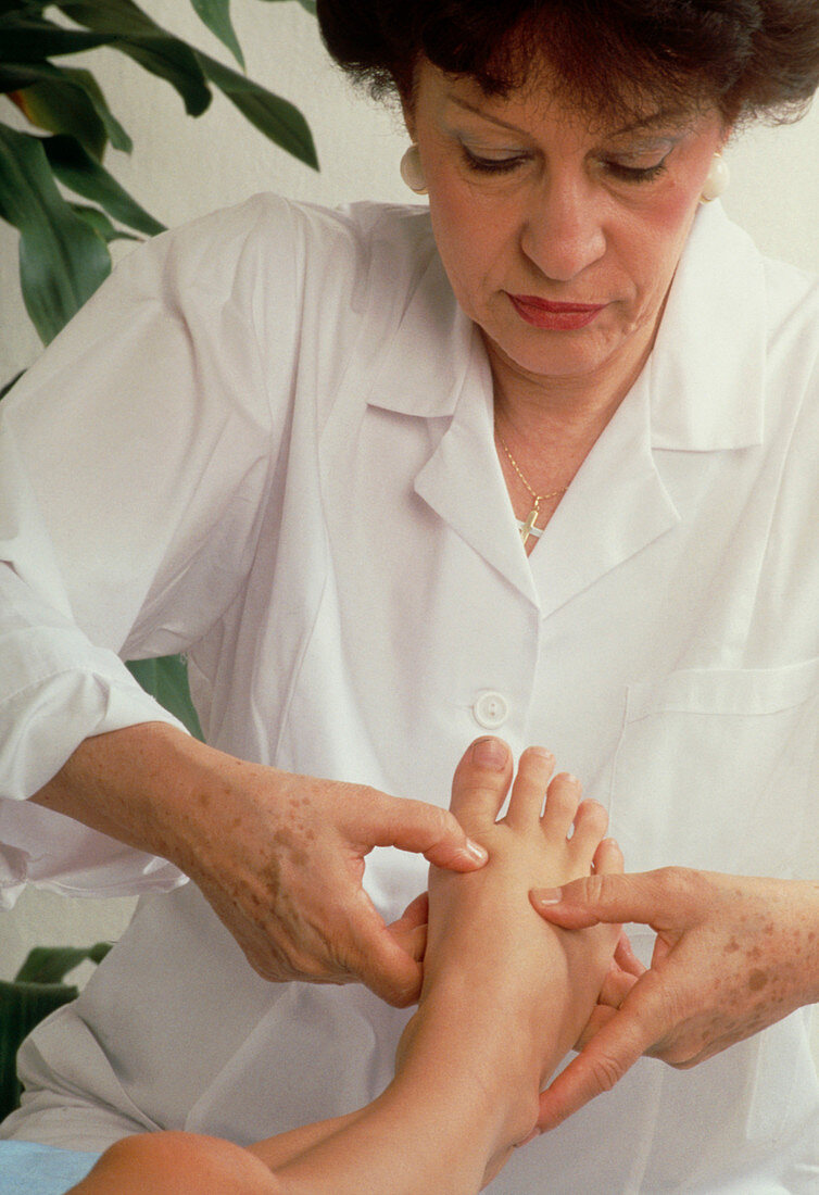 Reflexologist massaging a woman's foot