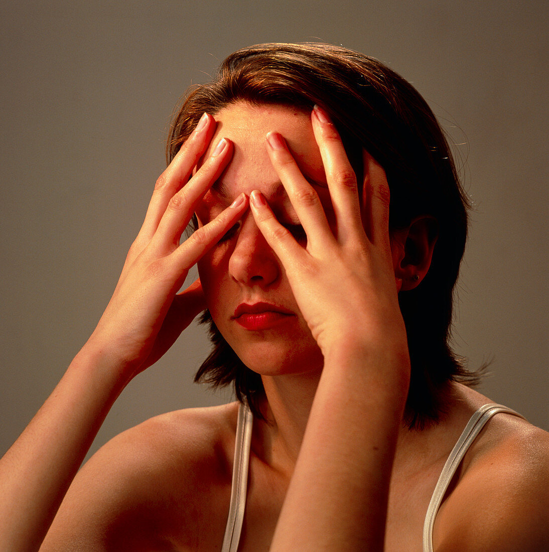 Meditating young woman's face with hands on eyes