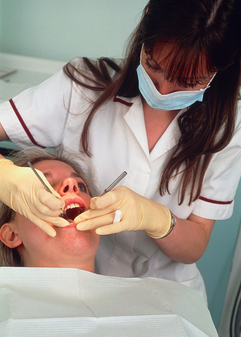Masked dentist checking the teeth of a patient