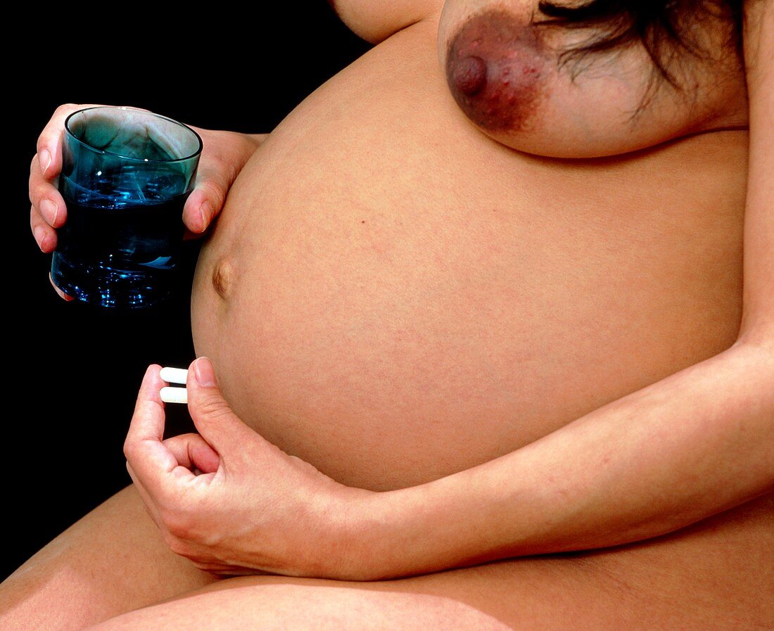 Pregnant woman taking pills with water