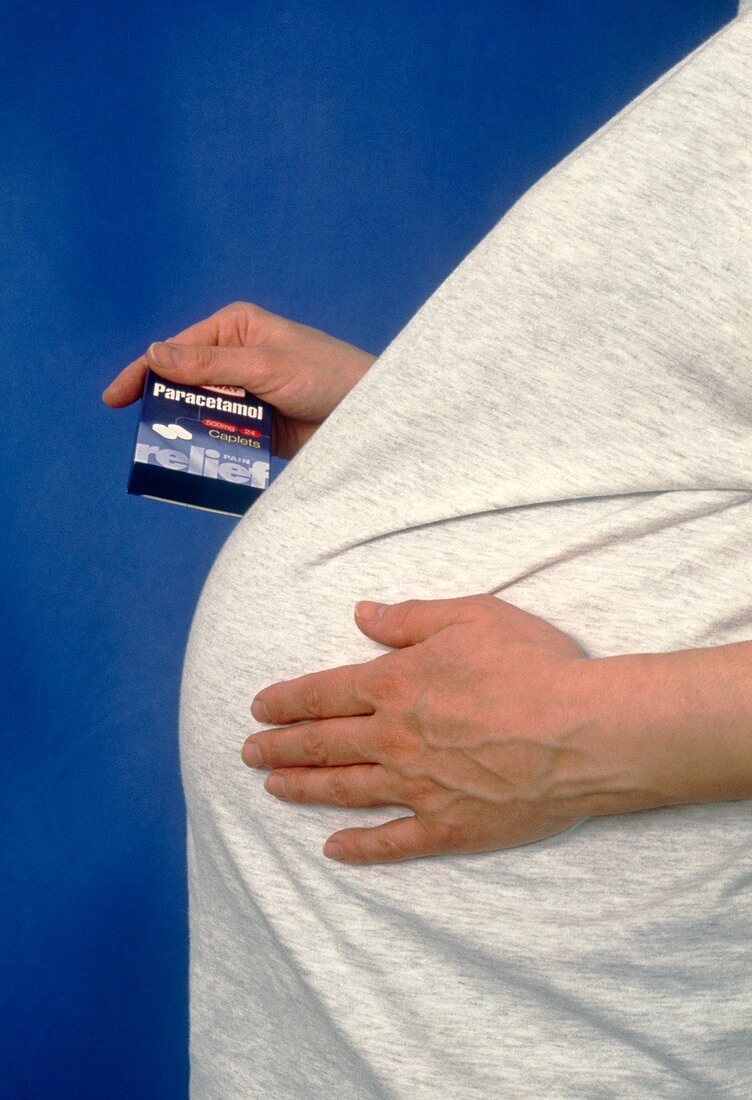 Pregnant woman's hand holding box of paracetamol