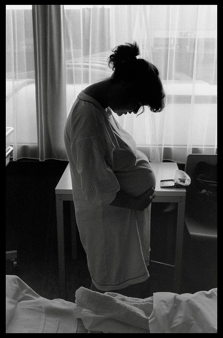 Pregnant woman in labour stands in a hospital ward