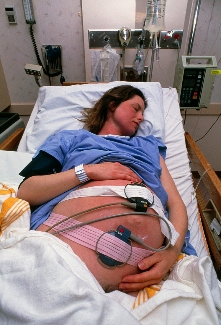 Woman in early labour resting on a hospital bed