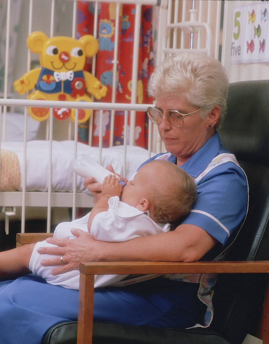 Nurse feeding baby in hospital