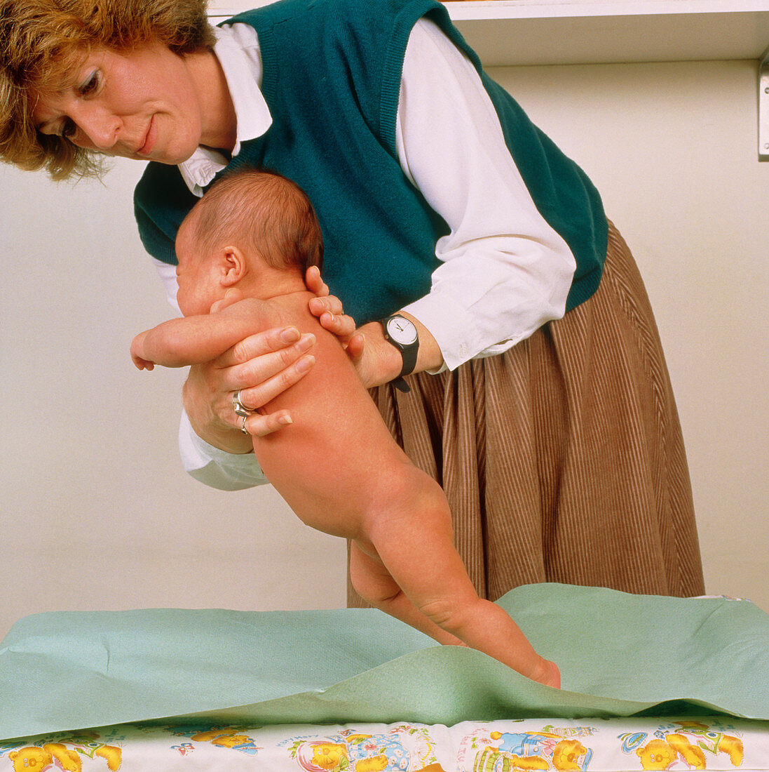 Doctor testing the stepping reflex of a baby
