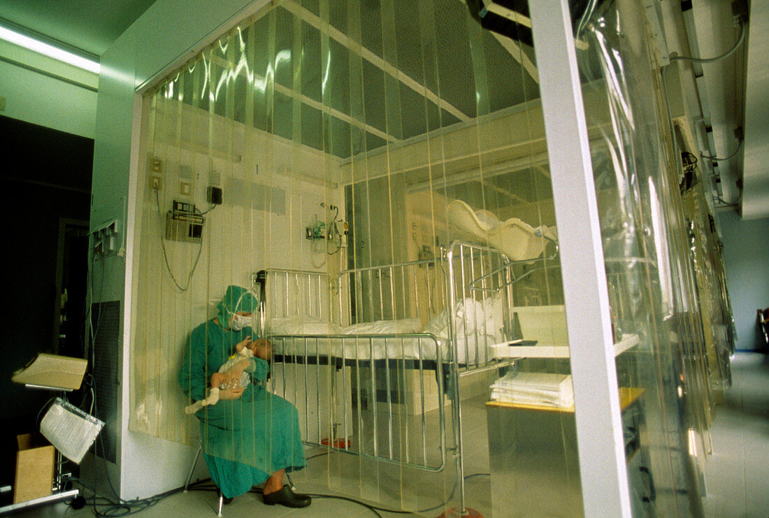 Nurse holds immunodeficient baby in sterile room