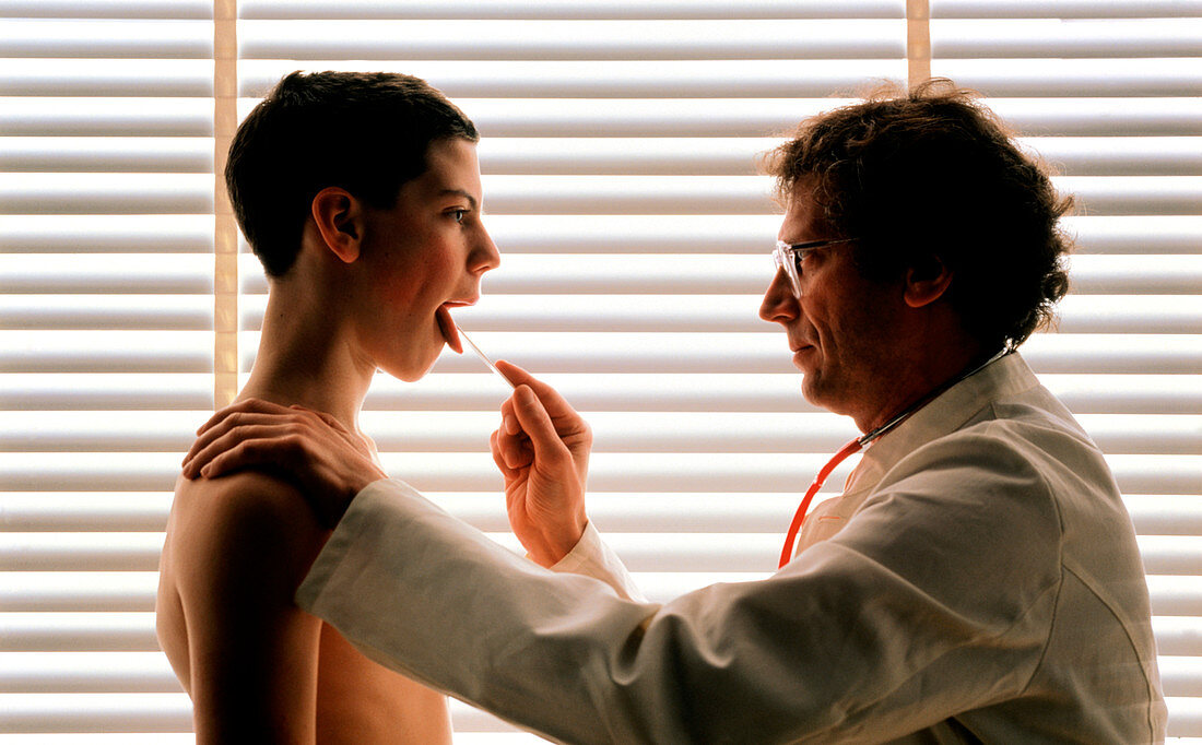 Doctor uses a spatula to examine a boy's throat