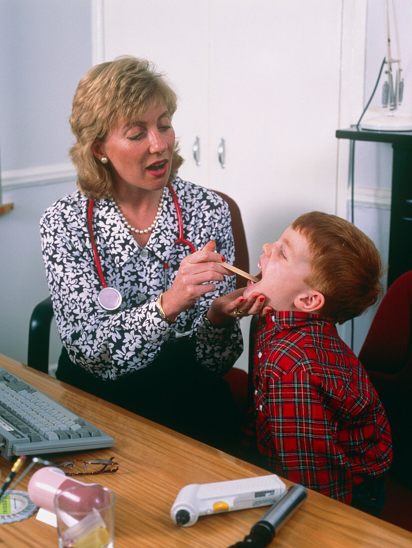 Doctor examining the throat of small boy