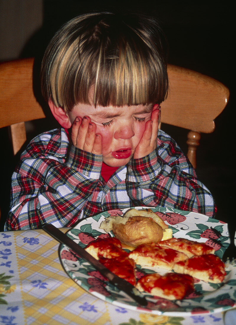 Angry two-year-old boy has a tantrum during dinner