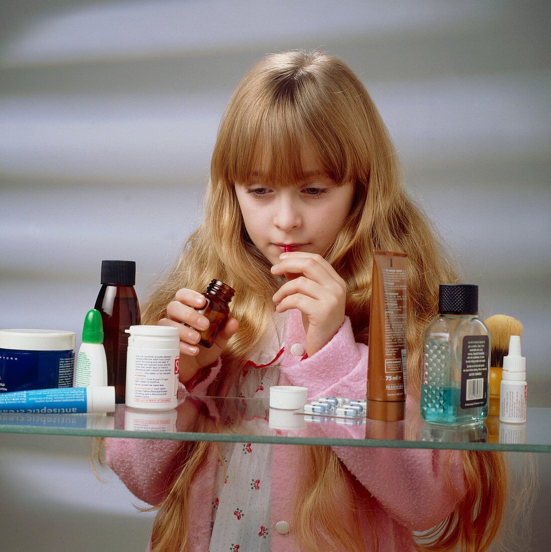 Child danger: young girl finds pills on a shelf