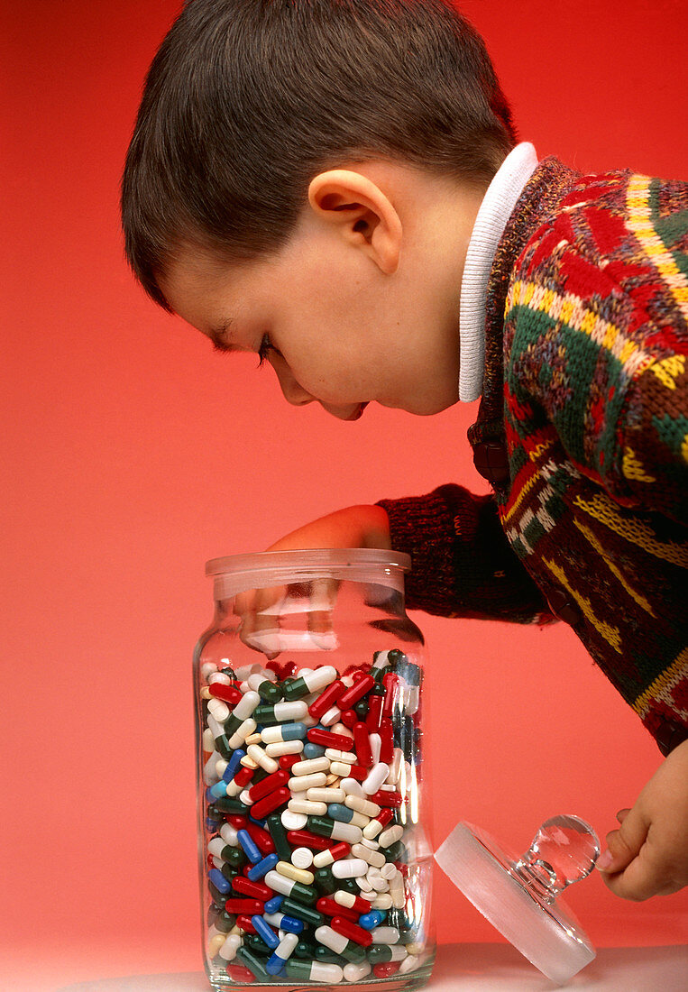 Boy taking pills and drug capsules from a jar