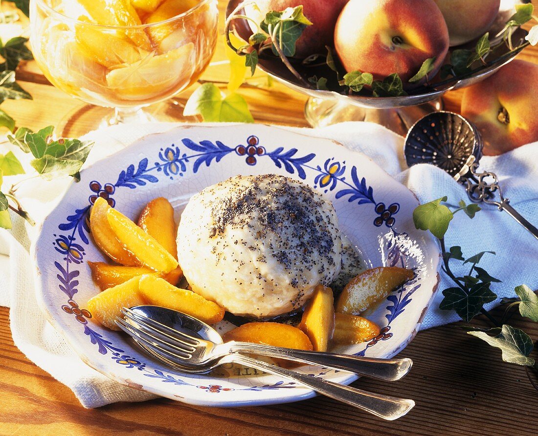 Germknödel mit gedünsteten Pfirsichspalten auf Teller