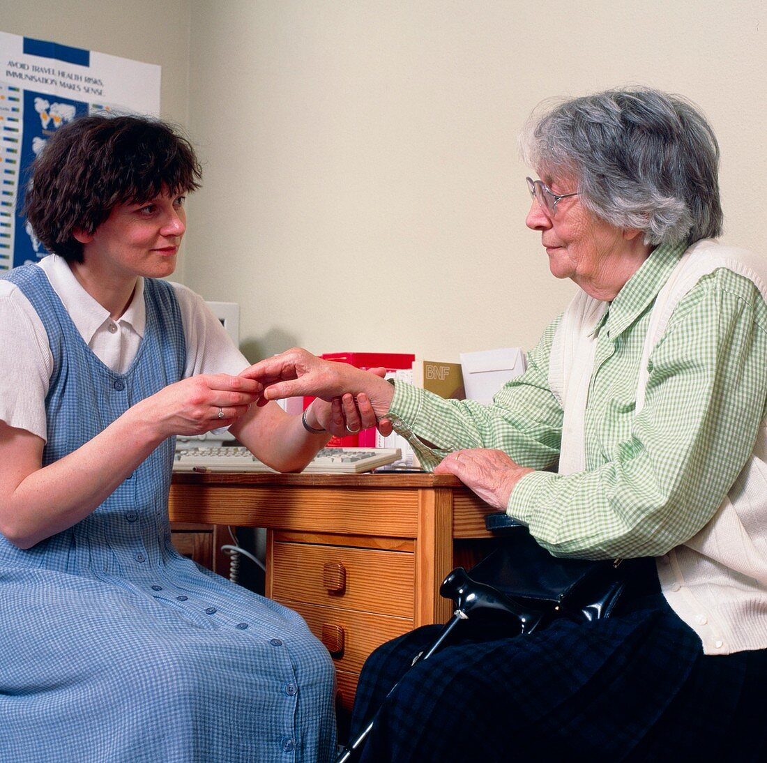 GP doctor examines an old woman's arthritic hand