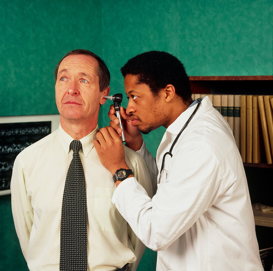 GP doctor examining a man's ear using an otoscope