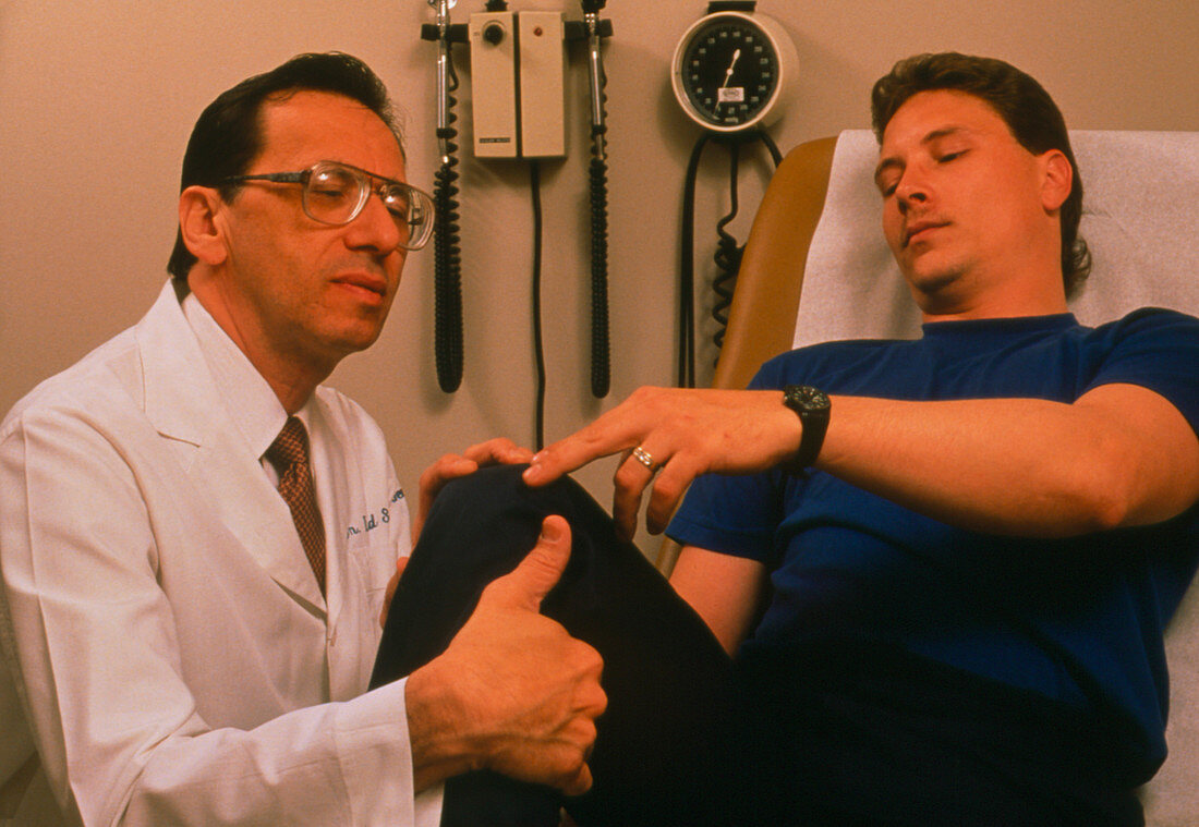 Doctor examines the knee joint of a male patient