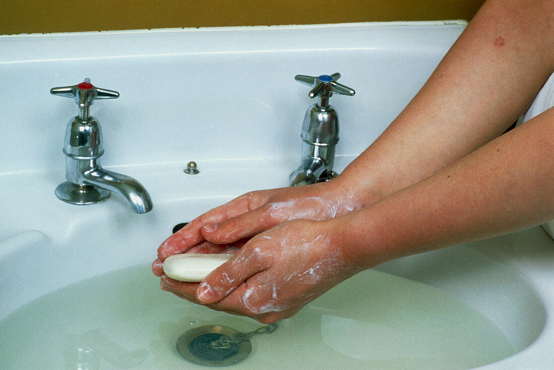 Woman washes hands at sink using soap and water