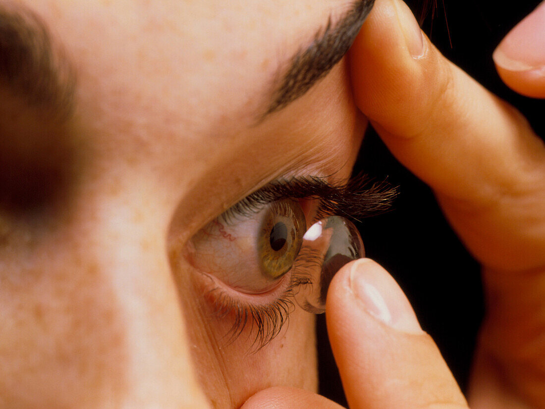Woman fitting a contact lens onto her eye