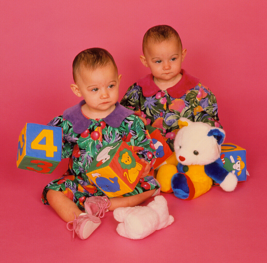 Infant identical twin girls (1 year old) with toys