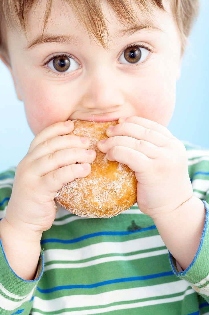 Toddler eating a jam doughnut