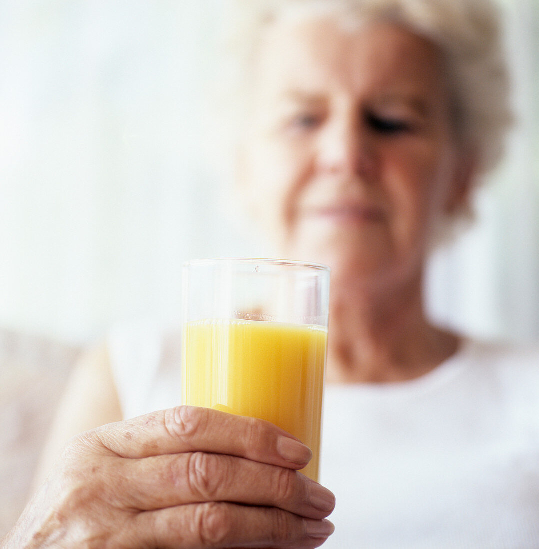 Elderly woman holding glass of juice