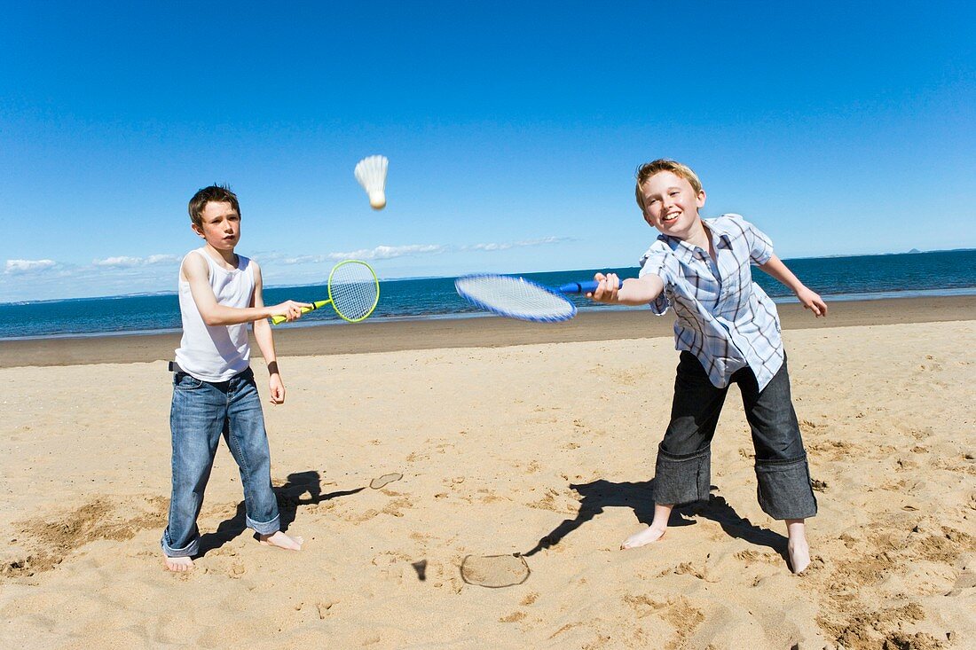 Boys playing badminton on a beach