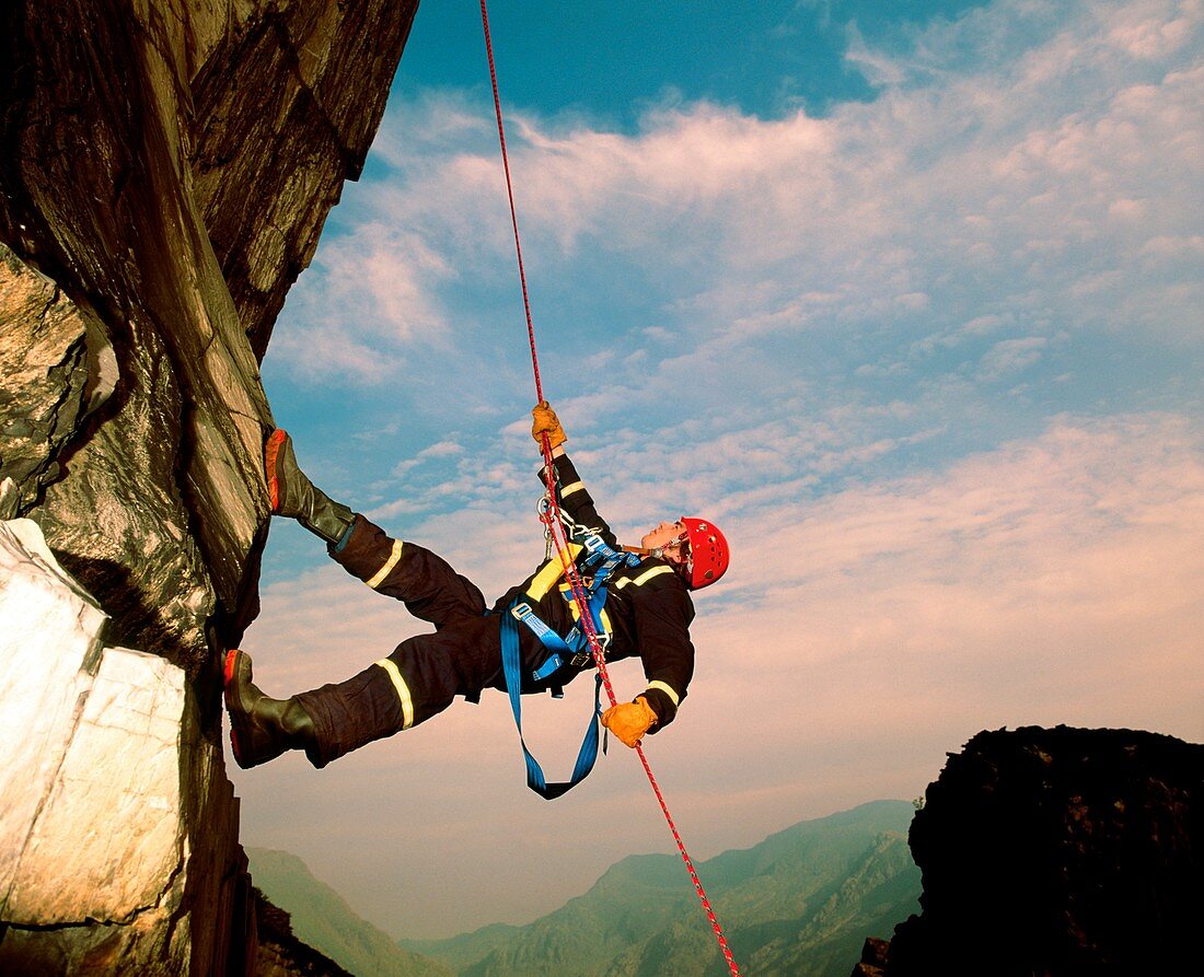 Rock climber abseiling down a rock face