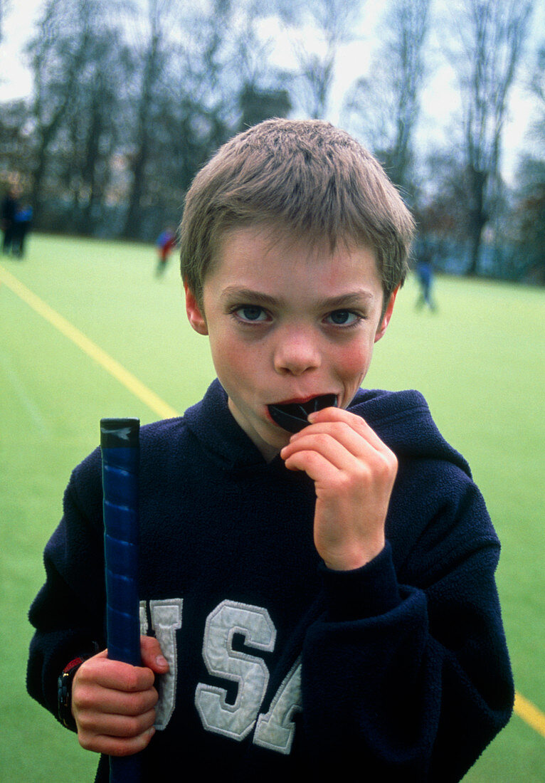 Boy putting gumshield in mouth for hockey game