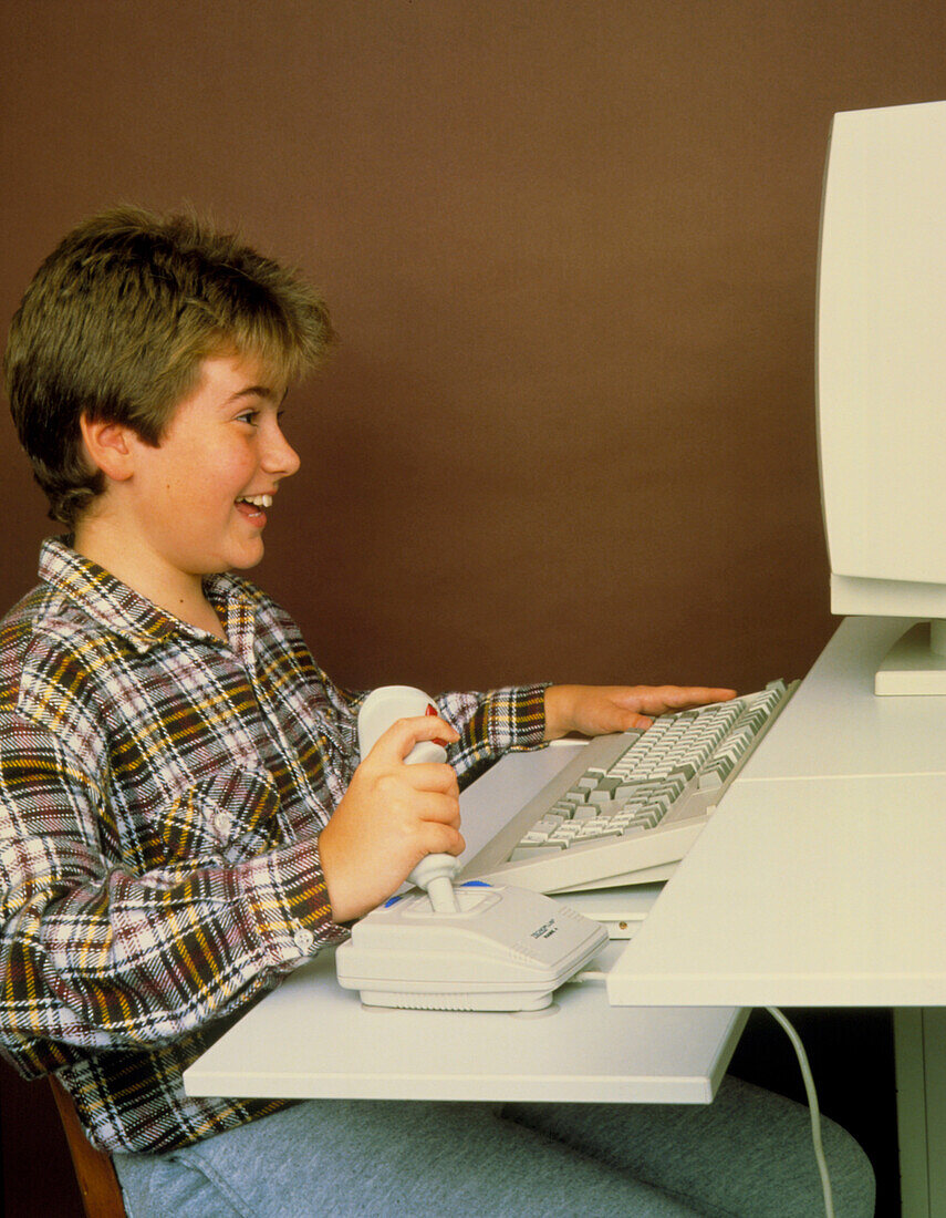 Boy playing computer game using joystick