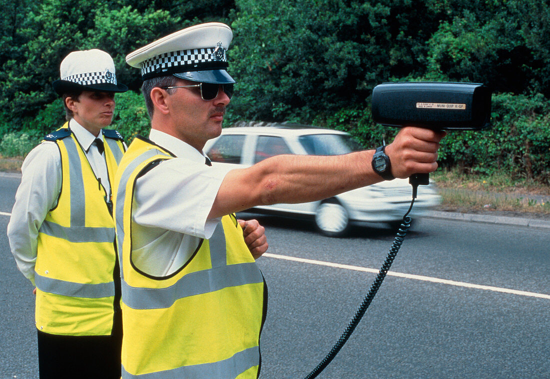 Policeman using radar gun to detect speeding car