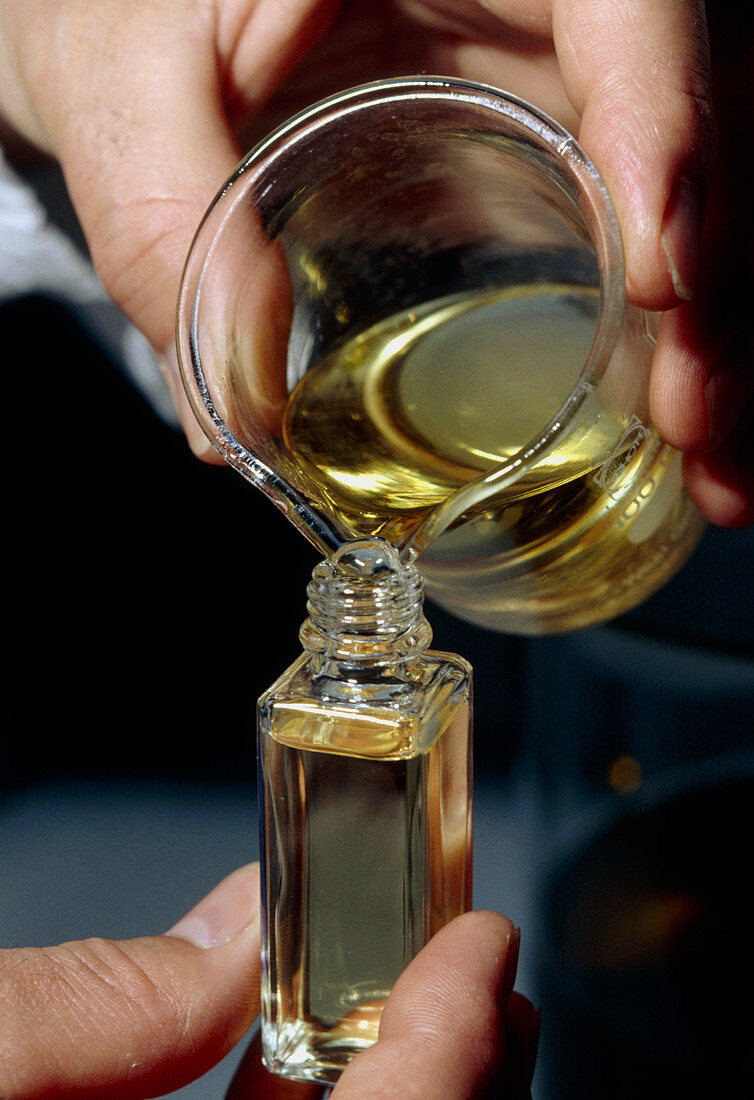 Filling a sample bottle with perfume from a beaker