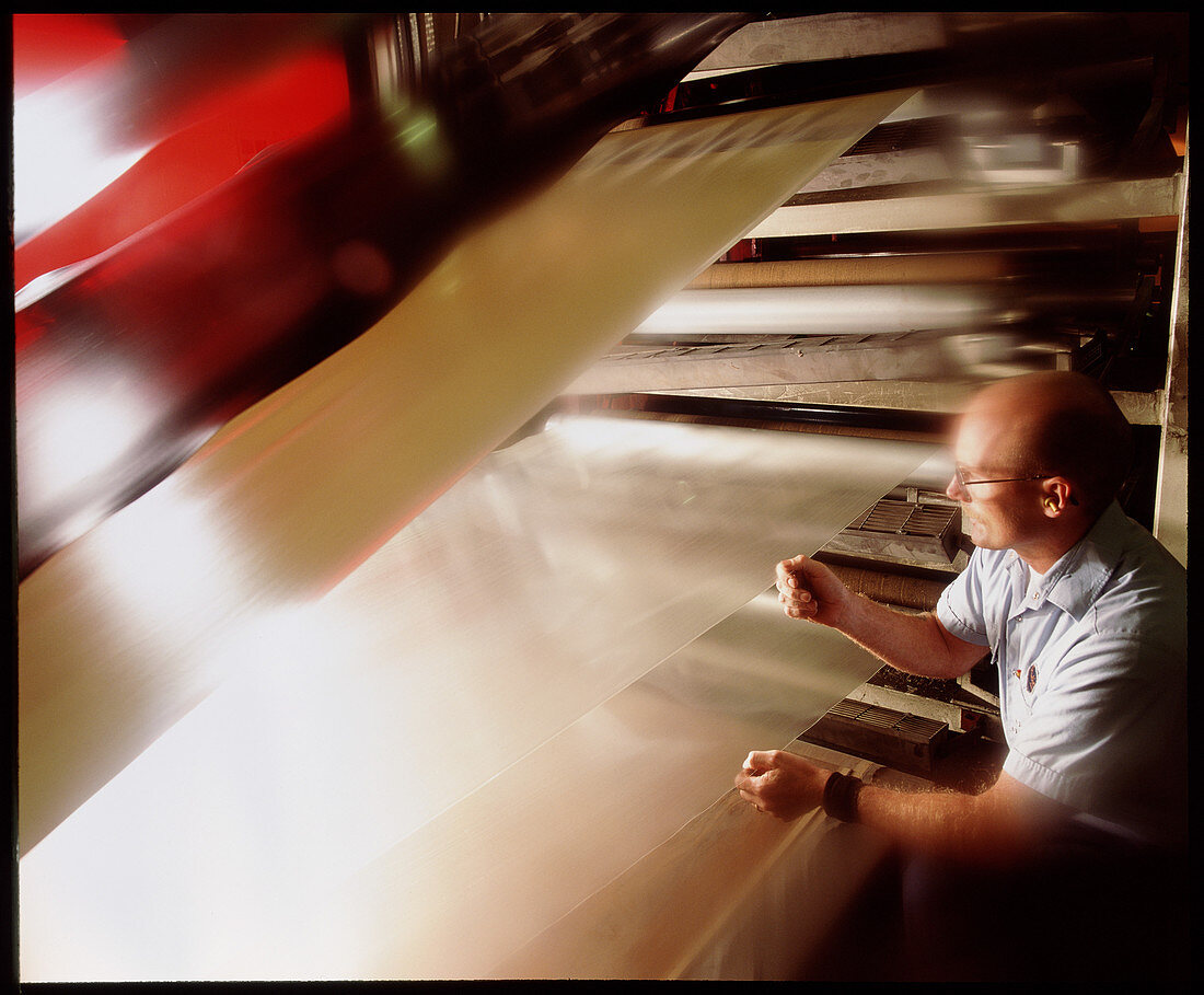 Worker checks the quality of film used in flooring