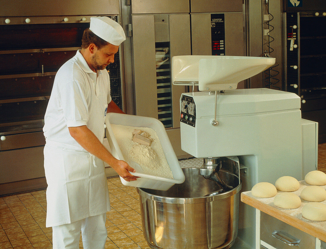 Baker putting bread ingredients into a machine