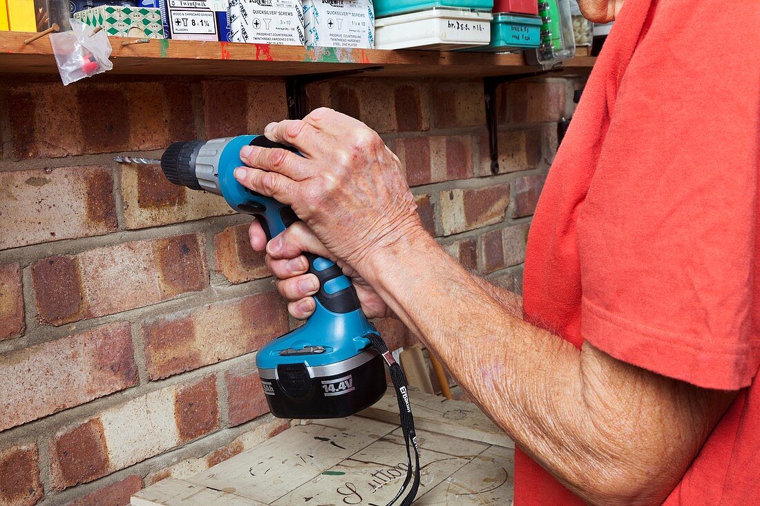 Elderly man using an electric drill