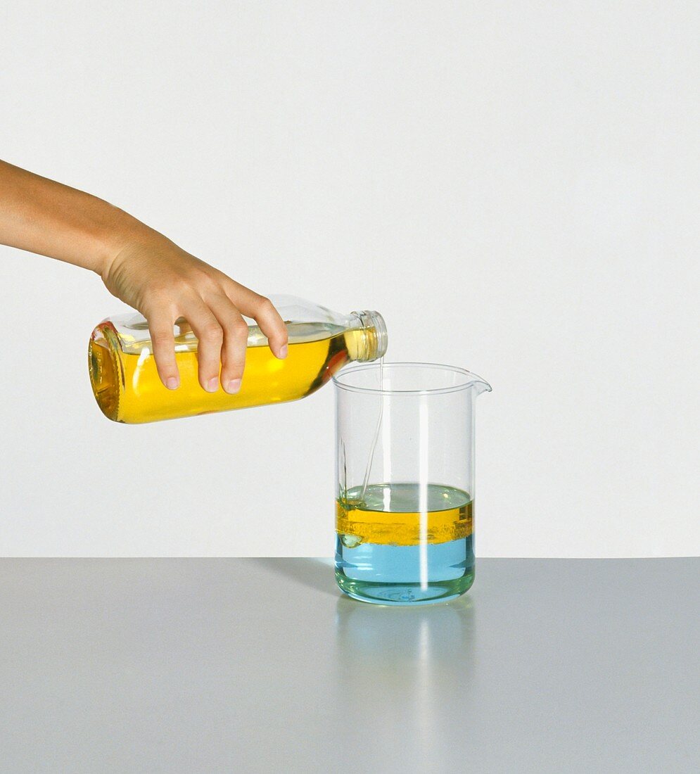 Hand pouring cooking oil over water