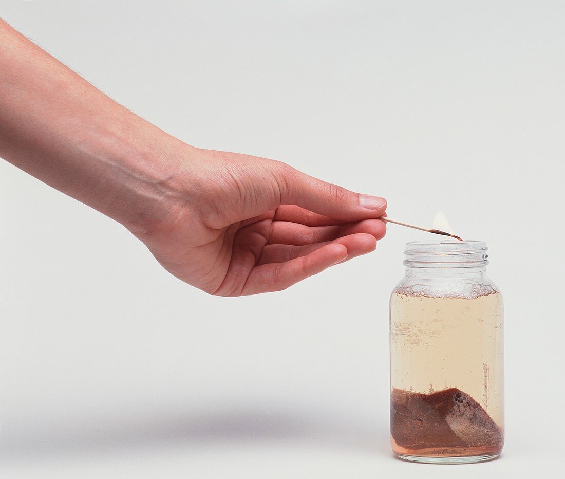 Hand holding lit match over jar