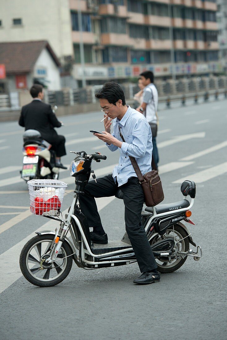 Man on a battery-powered moped smoking