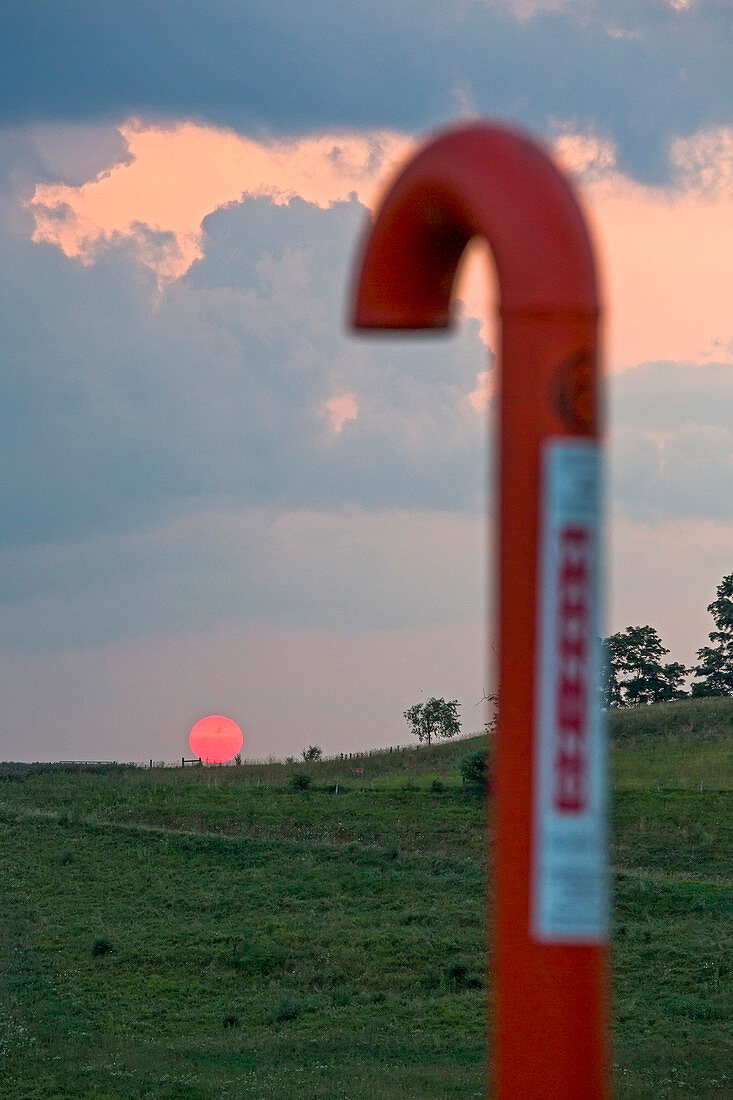 Natural gas pipeline marker at sunset