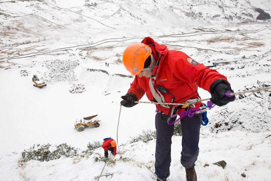 Mountain rescue team member abseiling