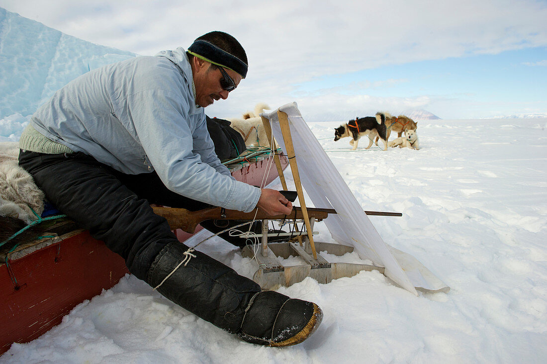 Inuit hunter with rifle and hunting blind