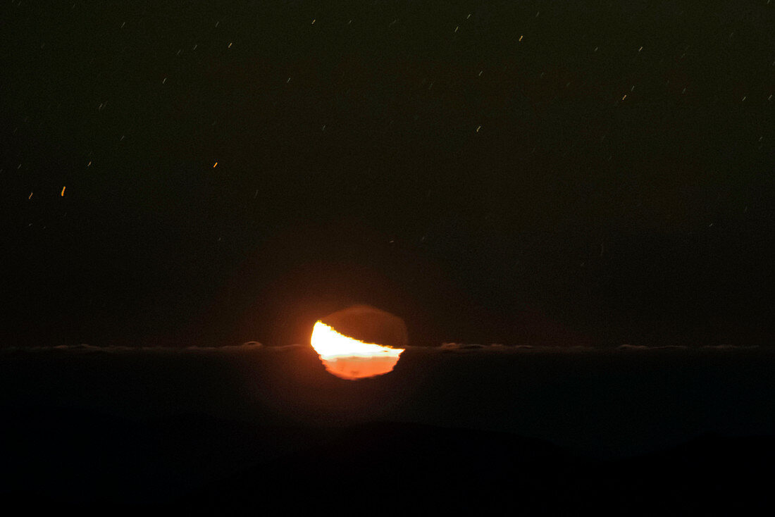 Moon setting behind an inversion layer