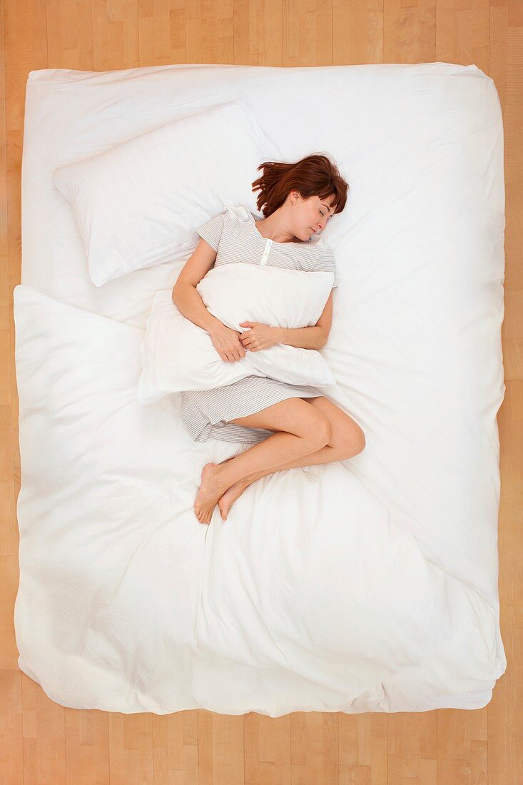 Woman lying in bed holding pillow