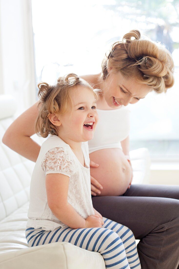 Pregnant woman and daughter smiling