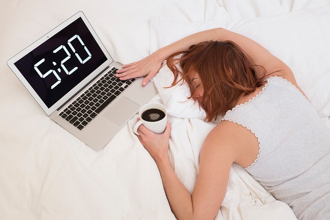 Exhausted woman in bed with laptop