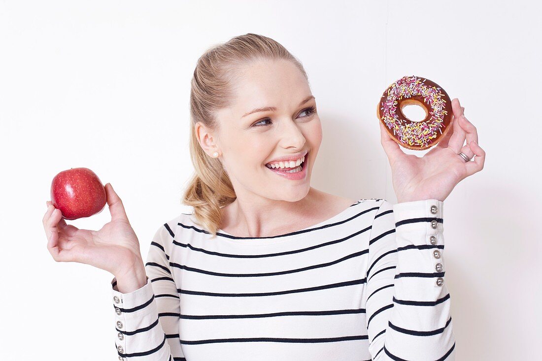 Pregnant woman holding apple and doughnut