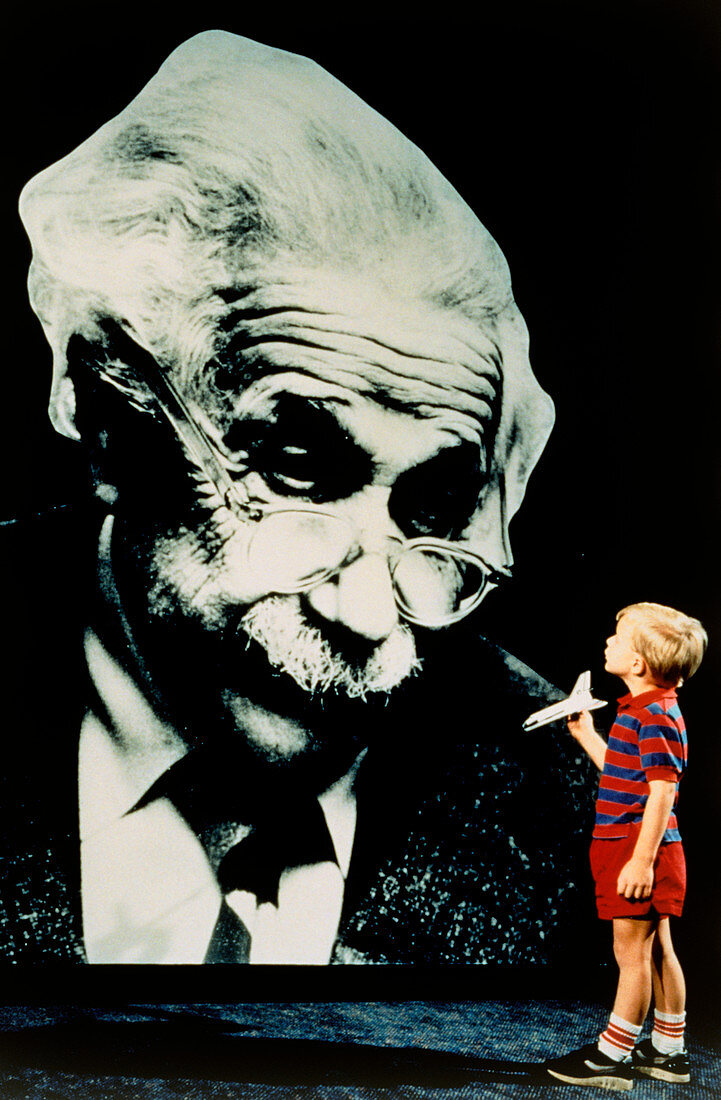 Small boy looks up at a photo of Albert Einstein