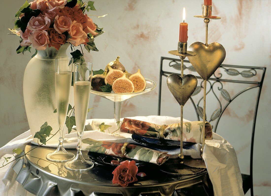 Romantisch gedeckter Tisch für zwei: Rosen, Sekt, Teller