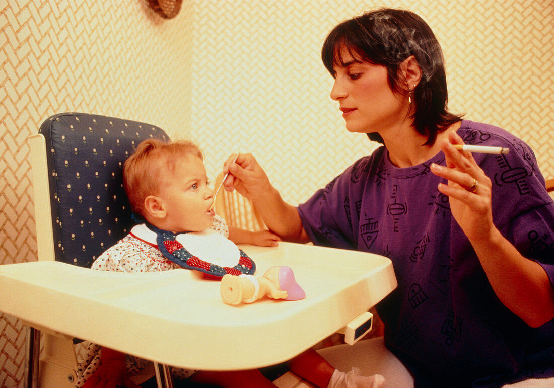 Mother smoking whilst feeding a baby